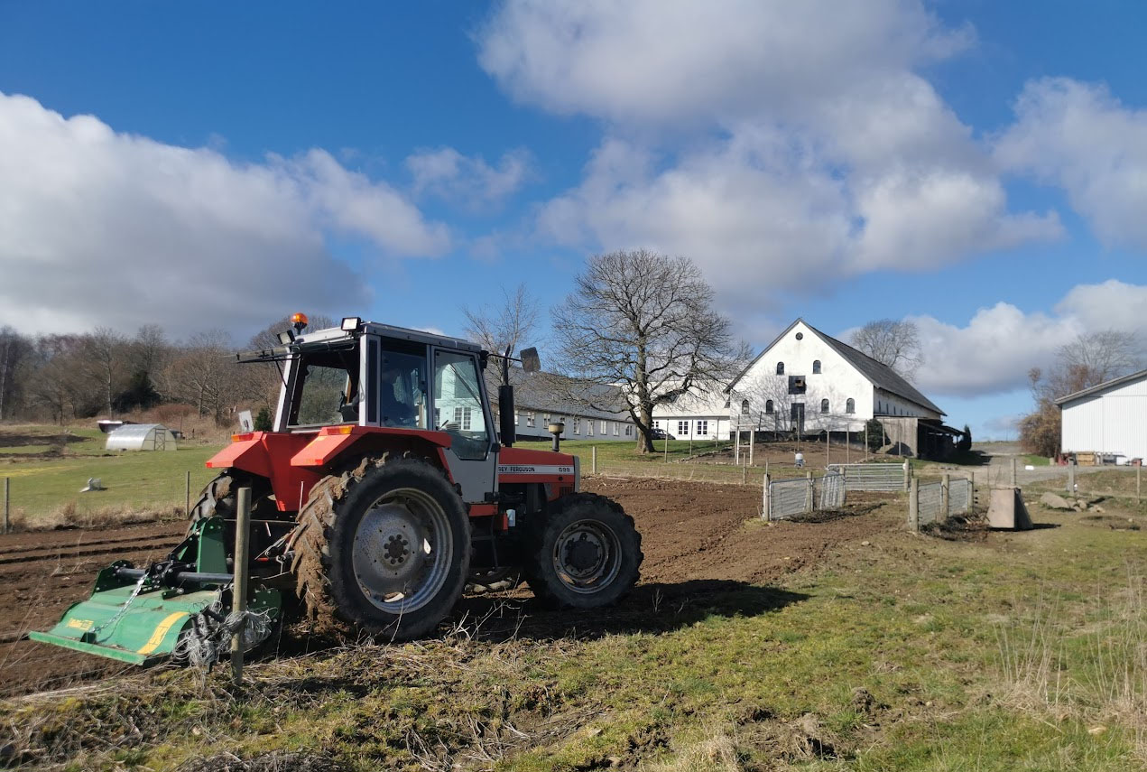 Traktor med gård i baggrund